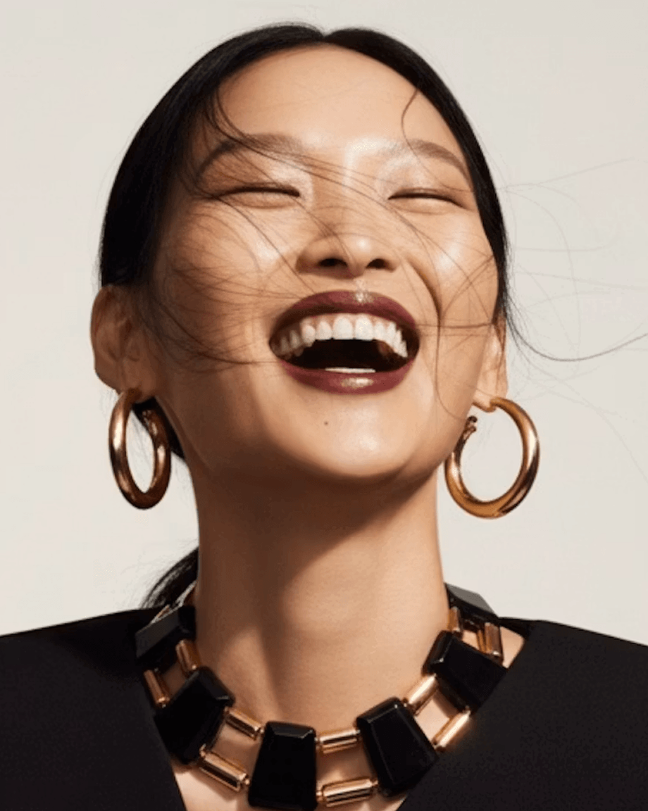 Woman laughing in gold hoop earrings and a bold necklace